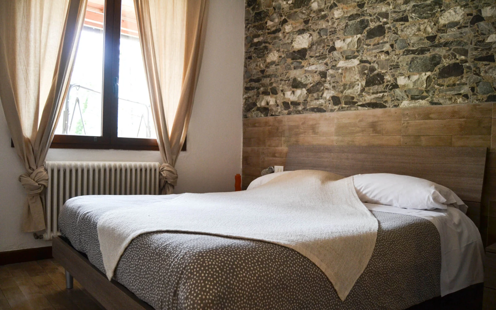 La camera della Casetta del Nonno Paco, con parete in pietra e arredi in legno